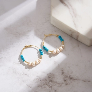Detail of bohemian turquoise beaded earrings with natural freshwater pearls on marble