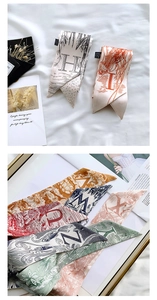 Detail of elegant alphabet silk twilly scarves with vintage art prints and floral patterns