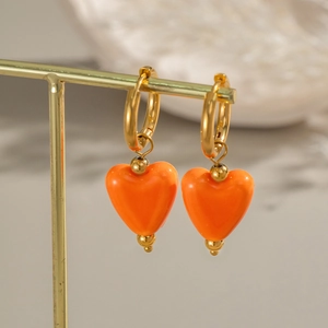 Créoles dorées avec pendentifs cœur orange présentées sur un support en métal minimaliste