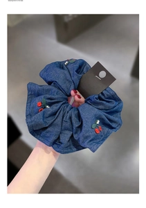 Detailed view of navy blue denim scrunchie with cherry embroidery and white pearls