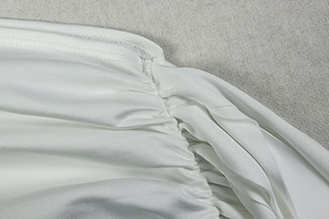 Detail of white pleated fabric texture with subtle sheen on asymmetric bodycon dress