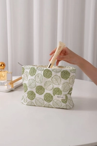 Close-up of cotton linen makeup bag with green leaf embroidery and metal zipper detail