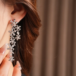 Macro detail of silver flower tassel earring with sparkling cubic zirconia on model