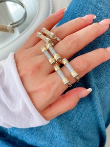 Macro view of crystal-encrusted gold and silver cylindrical stacked rings on hand