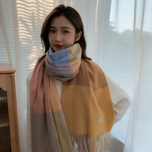 Detail of soft multicolored plaid scarf featuring pastel tones and long fringe tassels