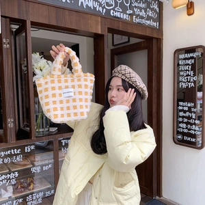 Close-up of fluffy yellow and white checkerboard plush tote bag with embroidered label