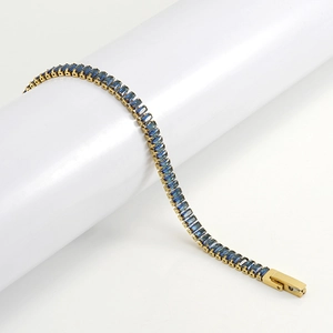Detail of gold-plated tennis bracelet featuring baguette-cut deep blue cubic zirconia