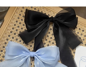 Detail of oversized organza ribbon hair bows in black and blue on a vintage tray
