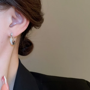 Close-up of a silver twisted double hoop earring with sparkling pavé rhinestones on model