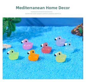 Close-up of colorful luminous resin flamingo figurines set in blue decorative sand