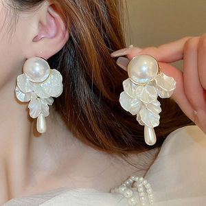 Detail of French style pearl flower drop earrings with white resin petals and gold base