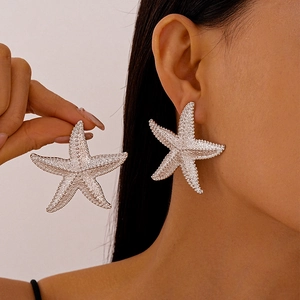 Macro detail of oversized starfish earring with embossed silver texture on model