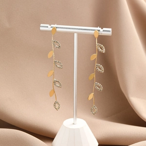 Detail of long gold vine leaf earrings with sparkling rhinestones on a display stand