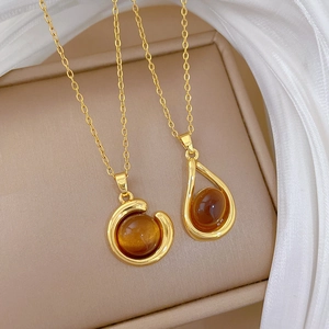 Luxurious gold necklaces with amber round and teardrop pendants on jewelry box