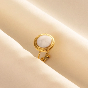 Detail of adjustable gold ring with white marble inlay on elegant silk background