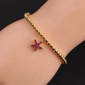 Bracelet en perles dorées polies avec un pendentif étoile en zircon violet