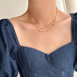 Close-up of a double-layered gold plated titanium necklace on model wearing denim