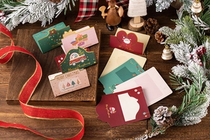 Close-up of 3D folding Christmas cards with Merry Christmas text among festive pine branches