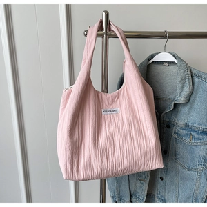 Detailansicht der rosa Falten-Tragetasche mit Kiss Yourself Etikett auf Denim