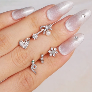 Exquisitos dijes de uñas plateados con perlas y pedrería en manicura brillante