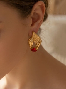 Close-up of gold shell tassel earrings with red zircon on model in soft natural light