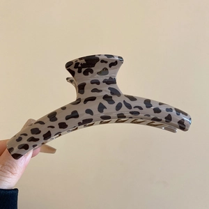 Detail of a large leopard print hair claw clip made of glossy acetate material