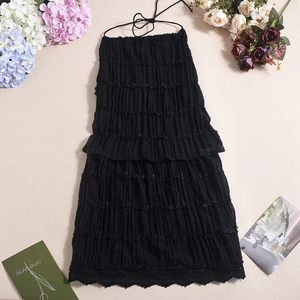 Detailed view of black tiered halter dress with ruffled texture and delicate lace hem