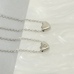 Minimalist heart-shaped initial necklace in polished stainless steel with letter D pendant