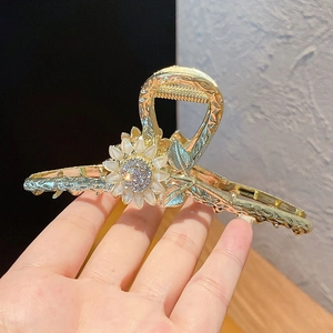 Detailed close-up of a sunflower hair claw with white petals and sparkling rhinestones