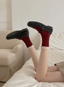 Detail of wool texture flat shoes with festive red lace-edge socks in lifestyle setting