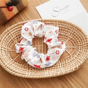 Close-up of fabric Christmas scrunchie with deer and star patterns in a woven basket