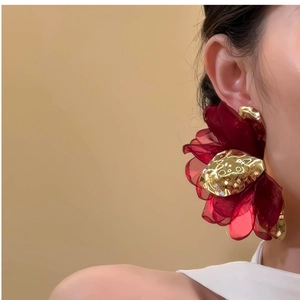 Close-up of model wearing large burgundy chiffon flower earrings with gold core