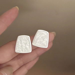 Detailed macro view of geometric silver earrings with white marble resin inlay texture