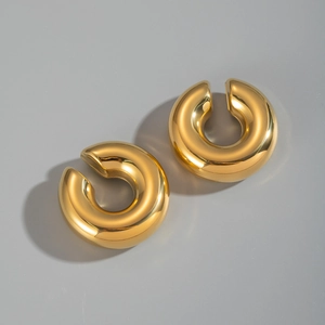 Close-up of highly polished C-shaped 18K gold-plated tube ear cuffs in golden finish