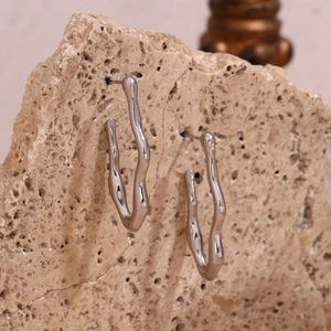 Macro view of silver wave-shaped earrings displayed on natural rock texture