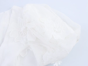 Close-up of white mesh dress featuring 3D floral embroidery and delicate texture