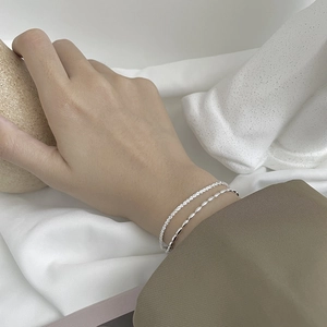 Detail of double-layered 925 silver bracelet featuring starburst and rice bead chains