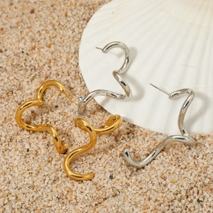 Polished spiral wave hoop earrings in gold and silver finish on a beach sand background