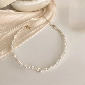 Macro detail of twisted pearl necklace featuring a sparkling rhinestone and gold clasp