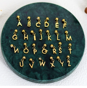 Close-up of 26 English gold alphabet pendants arranged on green marble display plate