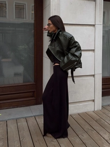 Detailed close-up of dark green oversized leather jacket with metallic zipper texture