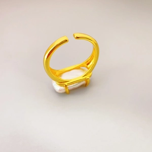 Retro gold open ring with rectangle baroque pearl inlay on a soft grey studio background