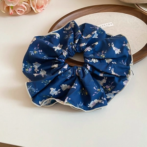 Close-up of deep blue scrunchie with rabbit floral pattern and white stitched edge