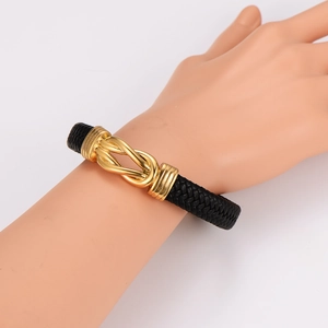 Détail d'un bracelet en cuir tressé noir avec un fermoir nœud magnétique doré poli
