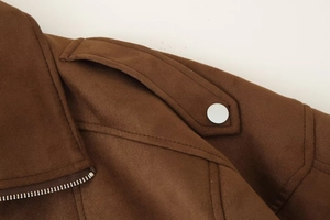Detail van de schouder van een bruin suède jack met epaulet, metalen knoop en rits