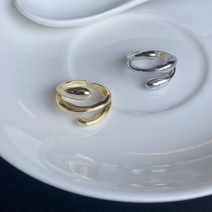 Detailed view of gold and silver S925 sterling silver water drop rings in a ceramic tray