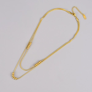 Detail of double-layer gold snake chain necklace with beads and K18D engraved tag