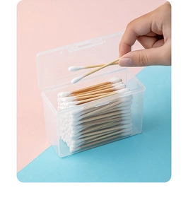 Detail of transparent storage box with wooden cotton swabs over pink and blue background