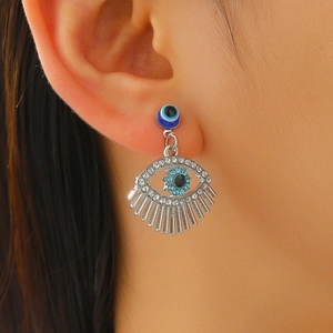 Detailed close-up of bohemian evil eye earrings with silver tassels and blue crystals