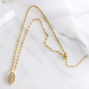 Detailed view of 18K gold leaf pendant with zircon micro-paving on a water wave chain